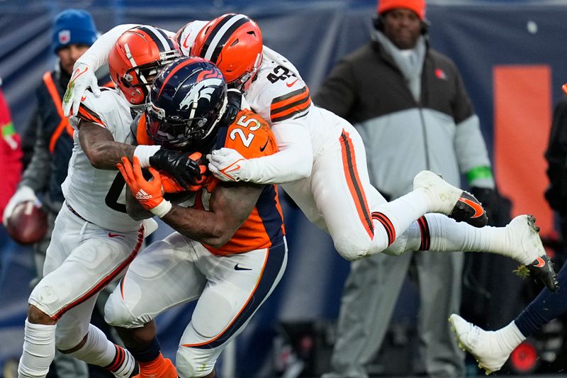 Denver Broncos running back Samaje Perine (25) struggles for yardage as Cleveland Browns cornerback Greg Newsome II and linebacker Tony Fields II, right, defends during the second half of an NFL football game on Sunday, Nov. 26, 2023, in Denver. (AP Photo/Jack Dempsey)