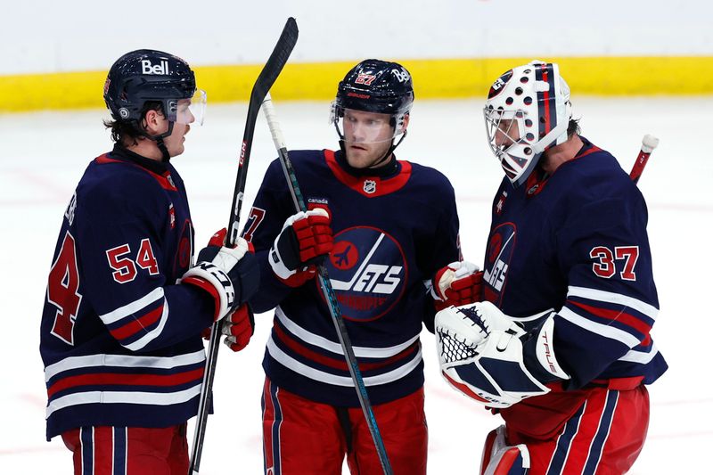 Nov 9, 2024; Winnipeg, Manitoba, CAN; Winnipeg Jets defenseman Dylan Samberg (54), Winnipeg Jets left wing Nikolaj Ehlers (27) and Winnipeg Jets goaltender Connor Hellebuyck (37) celebrate their victory over the Dallas Stars at Canada Life Centre. Mandatory Credit: James Carey Lauder-Imagn Images