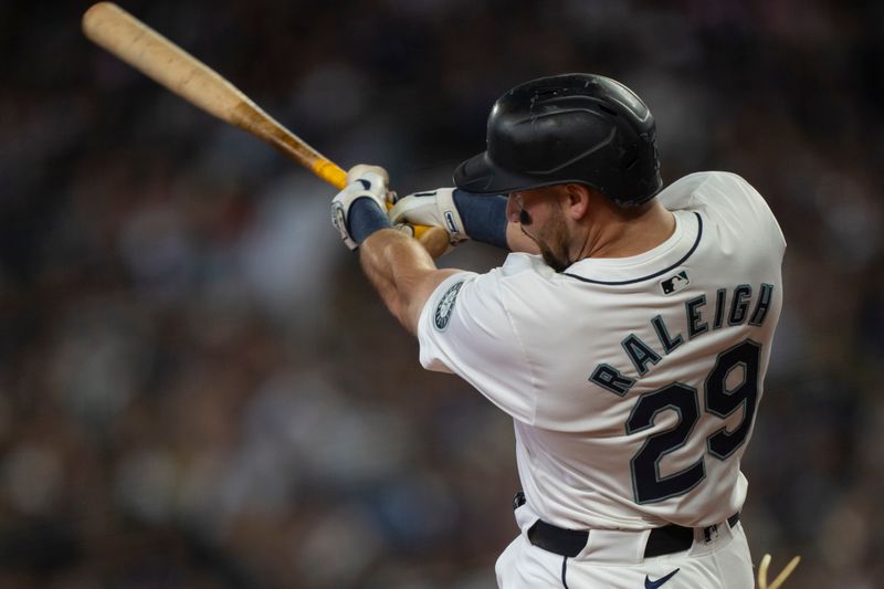 Jun 15, 2024; Seattle, Washington, USA; Seattle Mariners designated hitter Cal Raleigh (29) hits a RBI-single during the first inning against the Texas Rangers at T-Mobile Park. Mandatory Credit: Stephen Brashear-USA TODAY Sports