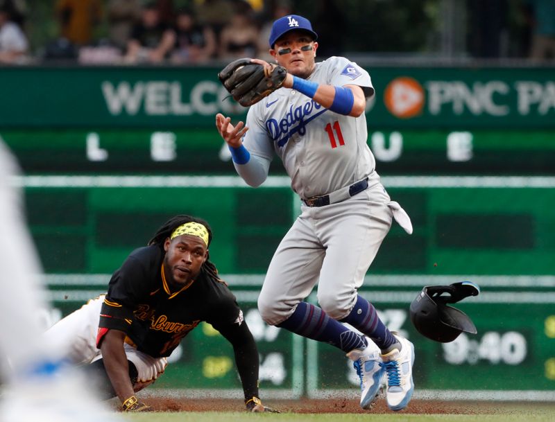 Jun 6, 2024; Pittsburgh, Pennsylvania, USA;  Los Angeles Dodgers second baseman Miguel Rojas (11) handles the ball on a double steal as Pittsburgh Pirates shortstop Oneil Cruz (left) is safe at second base during the third inning at PNC Park. Mandatory Credit: Charles LeClaire-USA TODAY Sports