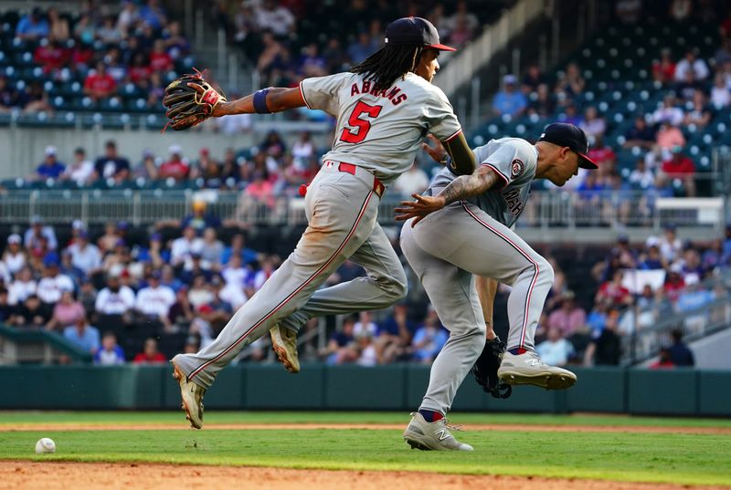 May 27, 2024; Cumberland, Georgia, USA; Atlanta Braves catcher Sean Murphy (12) hits an infield single on an error as Washington Nationals shortstop CJ Abrams (5) and Washington Nationals third baseman Nick Senzel (13) bobble the ball during the ninth inning at Truist Park. Mandatory Credit: John David Mercer-USA TODAY Sports