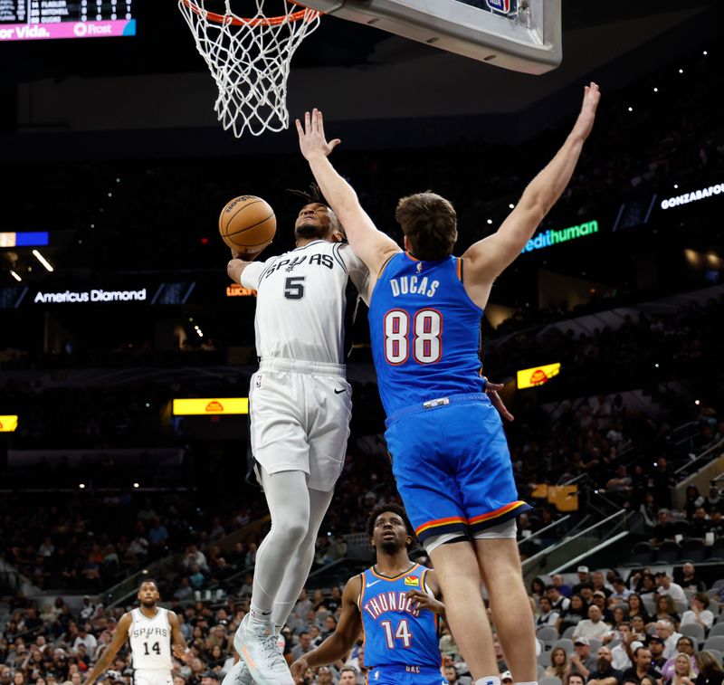 SAN ANTONIO, TX - OCTOBER 07:  Stephon Castle #5  of the San Antonio Spurs dunks over Alex Dugas #88 of the Oklahoma City Thunder in the second half of a preseason game at Frost Bank Center on October 7, 2024 in San Antonio, Texas. NOTE TO USER: User expressly acknowledges and agrees that, by downloading and or using this photograph, User is consenting to terms and conditions of the Getty Images License Agreement. (Photo by Ronald Cortes/Getty Images)