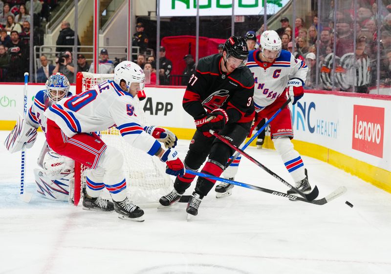 Nov 27, 2024; Raleigh, North Carolina, USA;  Carolina Hurricanes right wing Andrei Svechnikov (37) battles for the puck against New York Rangers defenseman Jacob Trouba (8) and left wing Will Cuylle (50) during the first period at Lenovo Center. Mandatory Credit: James Guillory-Imagn Images