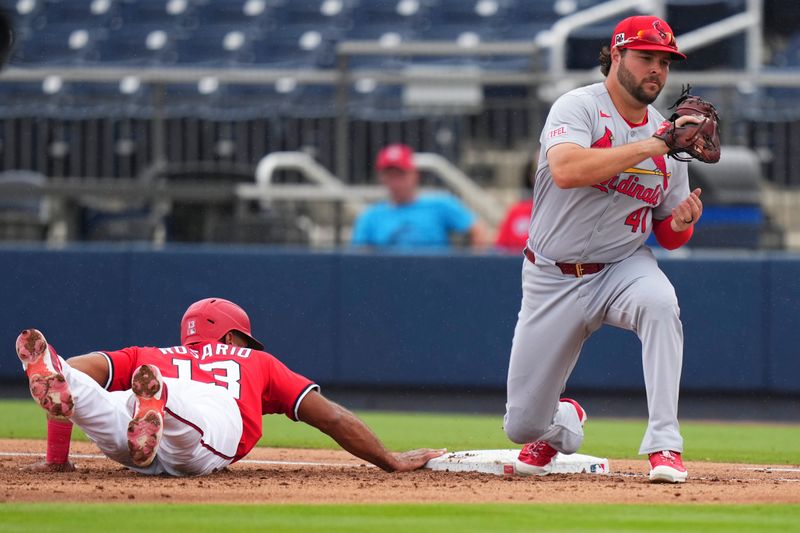 Mar 4, 2025; West Palm Beach, Florida, USA; Washington Nationals outfielder Amed Rosario (13) slides back into first base against St. Louis Cardinals outfielder Alec Burleson (41) during the third inning at CACTI Park of the Palm Beaches. Mandatory Credit: Rich Storry-Imagn Images