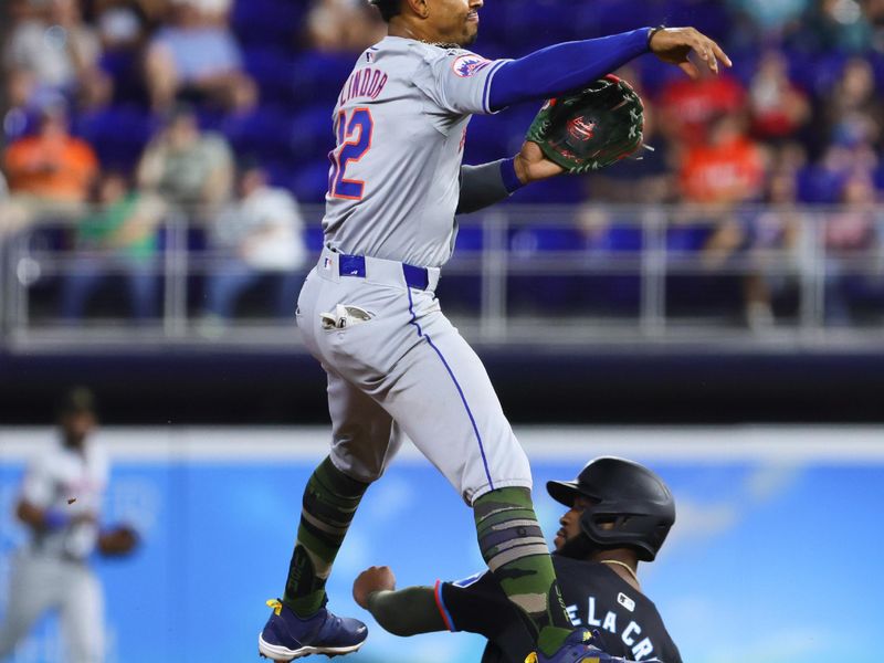 May 17, 2024; Miami, Florida, USA; New York Mets shortstop Francisco Lindor (12) turns a double play as Miami Marlins designated hitter Bryan De La Cruz (14) slides at second base during the first inning at loanDepot Park. Mandatory Credit: Sam Navarro-USA TODAY Sports