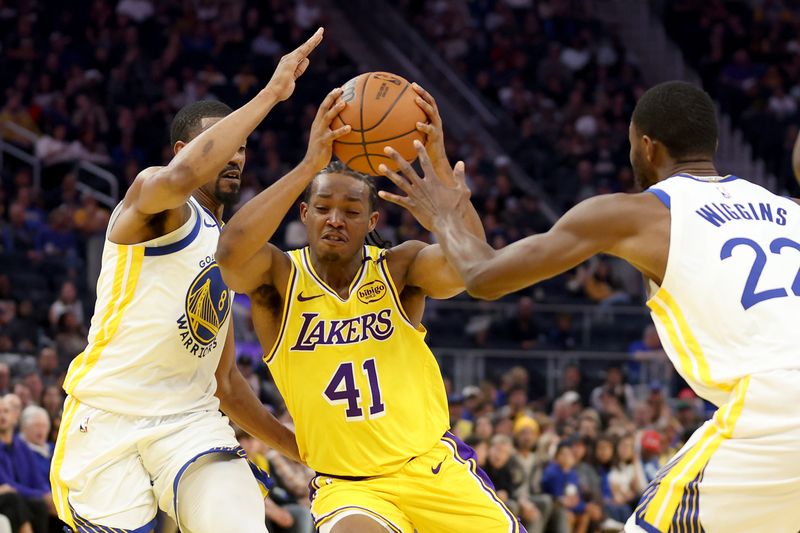 SAN FRANCISCO, CALIFORNIA - OCTOBER 18: Quincy Olivari #41 of the Los Angeles Lakers is guarded by De'Anthony Melton #8 and Andrew Wiggins #22 of the Golden State Warriors during the first half of their preseason game at Chase Center on October 18, 2024 in San Francisco, California.  NOTE TO USER: User expressly acknowledges and agrees that, by downloading and/or using this photograph, user is consenting to the terms and conditions of the Getty Images License Agreement.  (Photo by Ezra Shaw/Getty Images)