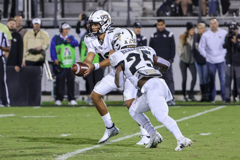 Nov 6, 2021; Orlando, Florida, USA; UCF Knights quarterback Mikey Keene (16) hands the ball off to running back Johnny Richardson (25) against the Tulane Green Wave during the second half at Bounce House. Mandatory Credit: Mike Watters-USA TODAY Sports