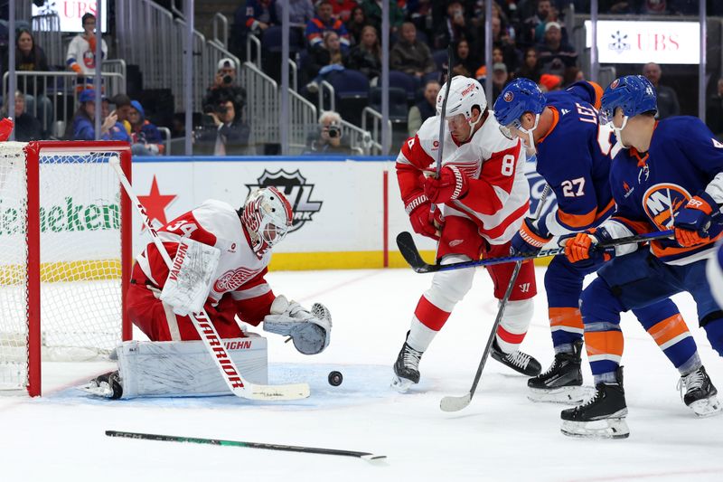 Oct 22, 2024; Elmont, New York, USA; Detroit Red Wings goaltender Alex Lyon (34) plays the puck against New York Islanders left wing Anders Lee (27) and center Jean-Gabriel Pageau (44) during the second period at UBS Arena. Mandatory Credit: Brad Penner-Imagn Images