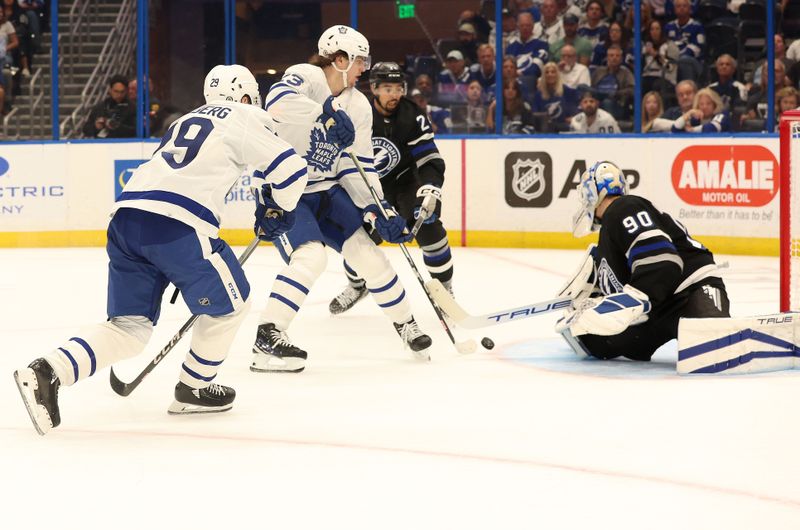 Apr 17, 2024; Tampa, Florida, USA; Toronto Maple Leafs right wing Pontus Holmberg (29) passes the puck as Tampa Bay Lightning goaltender Matt Tomkins (90) defends and Toronto Maple Leafs left wing Matthew Knies (23) and Tampa Bay Lightning defenseman Matt Dumba (24) look on during the second period at Amalie Arena. Mandatory Credit: Kim Klement Neitzel-USA TODAY Sports