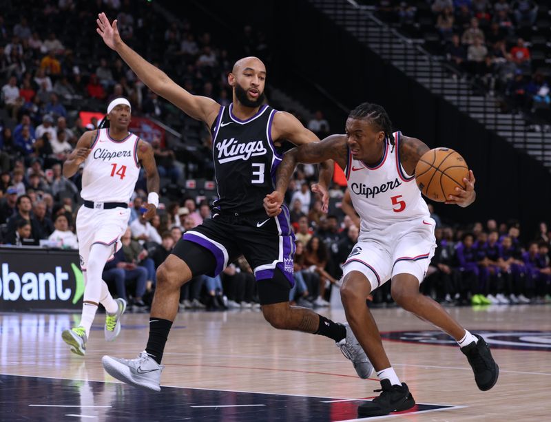 INGLEWOOD, CALIFORNIA - OCTOBER 17: Bones Hyland #5 of the LA Clippers reacts as he drives to the basket in front of Jordan McLaughlin #3 of the Sacramento Kings during the first half in a pre-season game at Intuit Dome on October 17, 2024 in Inglewood, California. (Photo by Harry How/Getty Images)