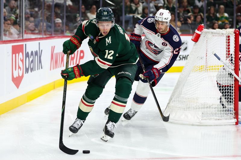 Oct 10, 2024; Saint Paul, Minnesota, USA; Minnesota Wild left wing Matt Boldy (12) skates with the puck as Columbus Blue Jackets center Sean Monahan (23) defends during the second period at Xcel Energy Center. Mandatory Credit: Matt Krohn-Imagn Images