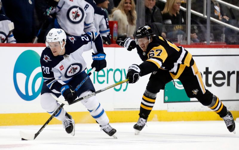 Jan 13, 2023; Pittsburgh, Pennsylvania, USA; Winnipeg Jets center Karson Kuhlman (20) skates with the puck as Pittsburgh Penguins right wing Rickard Rakell (67) chases during the first period  at PPG Paints Arena. Mandatory Credit: Charles LeClaire-USA TODAY Sports