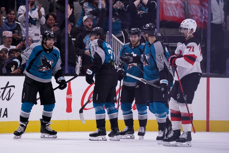 Oct 30, 2025; San Jose, California, USA;  San Jose Sharks defenseman Mario Ferraro (38), defenseman Timothy Liljegren (37), center Philipp Kurashev (96), and center Alexander Wennberg (21) celebrate after a goal as New Jersey Devils defenseman Jonas Siegethaler (71) looks on in the first period at SAP Center at San Jose. Mandatory Credit: David Gonzales-Imagn Images