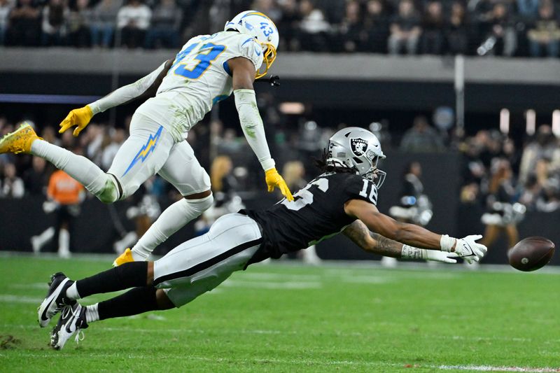 Las Vegas Raiders wide receiver Jakobi Meyers (16) misses a catch attempt beside Los Angeles Chargers cornerback Michael Davis (43) during the second half of an NFL football game, Thursday, Dec. 14, 2023, in Las Vegas. (AP Photo/David Becker)