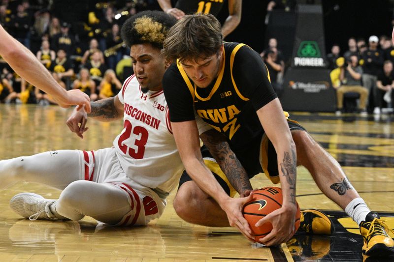 Feb 17, 2024; Iowa City, Iowa, USA; Iowa Hawkeyes forward Owen Freeman (32) and Wisconsin Badgers guard Chucky Hepburn (23) battle for a loose ball during the second half at Carver-Hawkeye Arena. Mandatory Credit: Jeffrey Becker-USA TODAY Sports