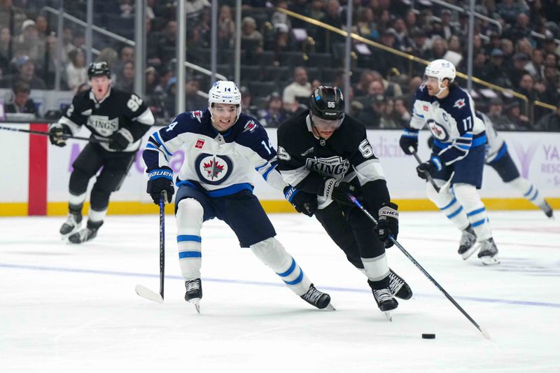 Nov 27, 2024; Los Angeles, California; LA Kings right wing Quinton Byfield (55) and Winnipeg Jets defenseman Ville Heinola (14) battle for the puck in the second period at Crypto.com Arena. Mandatory Credit: Kirby Lee-Imagn Images