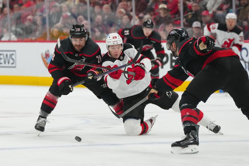 Mar 28, 2026; Raleigh, North Carolina, USA;  Carolina Hurricanes left wing William Carrier (28) checks New Jersey Devils right wing Lenni Hameenaho (29) during the second period at Lenovo Center. Mandatory Credit: James Guillory-Imagn Images