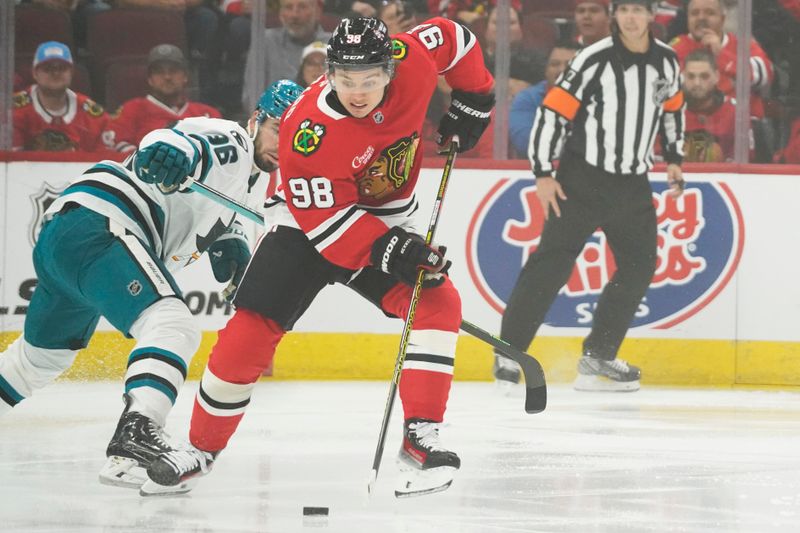 Oct 17, 2024; Chicago, Illinois, USA; Chicago Blackhawks center Connor Bedard (98) and San Jose Sharks defenseman Jake Walman (96) go for the puck during the first period at United Center. Mandatory Credit: David Banks-Imagn Images