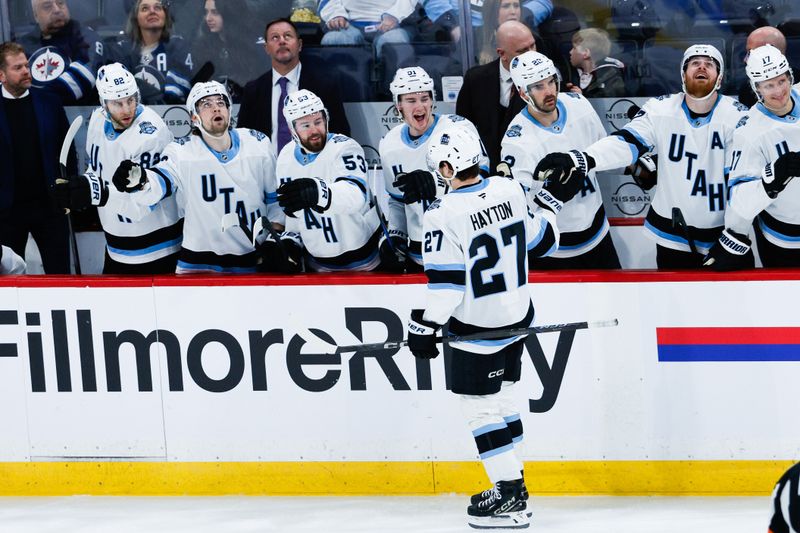Jan 24, 2025; Winnipeg, Manitoba, CAN; Utah Hockey Club forward Barrett Hayton (27) is congratulated by his teammates on his goal against Winnipeg Jets goalie Connor Hellebuyck (not pictured) during the third period at Canada Life Centre. Mandatory Credit: Terrence Lee-Imagn Images