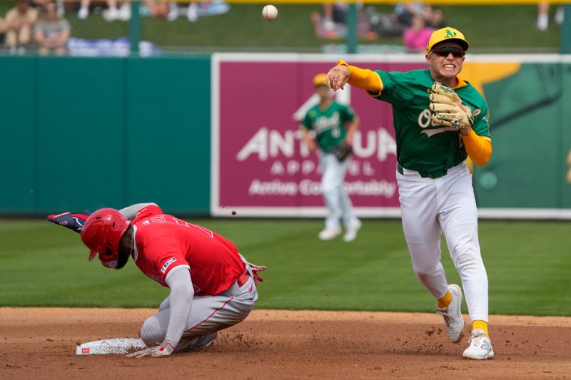 Mar 23, 2024; Mesa, Arizona, USA; Oakland Athletics shortstop Nick Allen (10) turns the double play while avoiding Los Angeles Angels left fielder Jo Adell (7) in the first inning at Hohokam Stadium. Mandatory Credit: Rick Scuteri-USA TODAY Sports