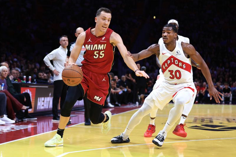 MIAMI, FLORIDA - NOVEMBER 29: Duncan Robinson #55 of the Miami Heat drives against Ochai Agbaji #30 of the Toronto Raptors during the first quarter of the Emirates NBA Cup at Kaseya Center on November 29, 2024 in Miami, Florida. NOTE TO USER: User expressly acknowledges and agrees that, by downloading and or using this photograph, User is consenting to the terms and conditions of the Getty Images License Agreement. (Photo by Megan Briggs/Getty Images)