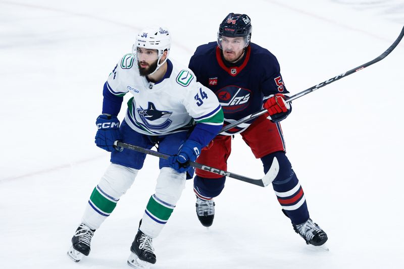 Jan 14, 2025; Winnipeg, Manitoba, CAN;  Winnipeg Jets defenseman Dylan Samberg (54) jostles for position withVancouver Canucks forward Phillip Di Giuseppe (34) during the third period at Canada Life Centre. Mandatory Credit: Terrence Lee-Imagn Images