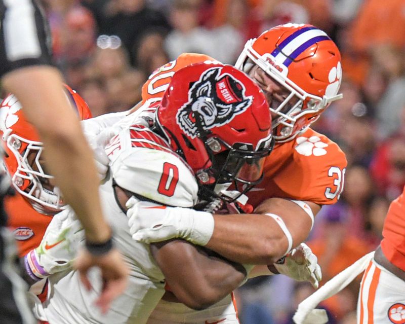 Oct 1, 2022; Clemson, South Carolina, USA; Clemson Tigers linebacker Keith Maguire (30) tackles North Carolina State Wolfpack running back Demie Sumo-Karngbaye (0) during the third quarter at Memorial Stadium. Mandatory Credit: Ken Ruinard-USA TODAY Sports