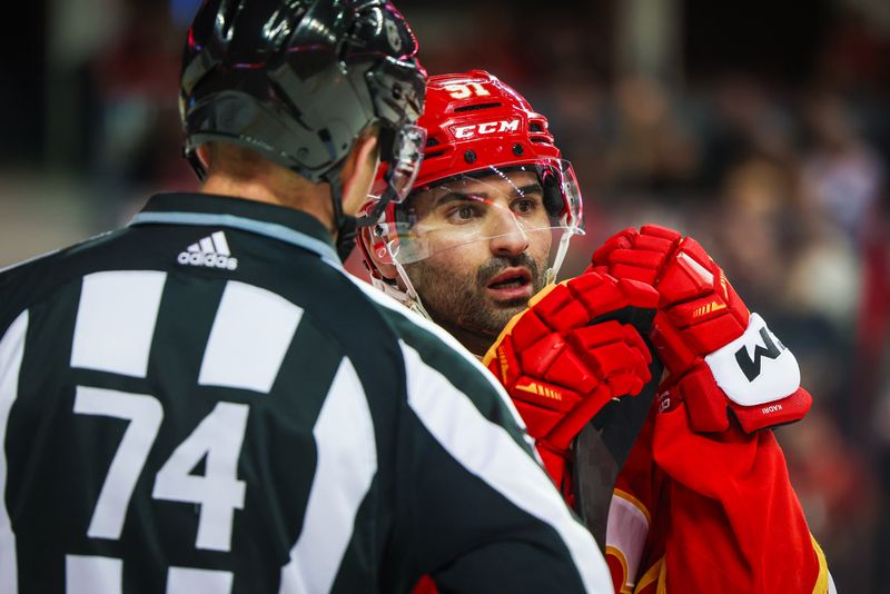 Dec 27, 2023; Calgary, Alberta, CAN; Calgary Flames center Nazem Kadri (91) and linesman Trent Knorr (74) exchanges words during the second period against the Seattle Kraken at Scotiabank Saddledome. Mandatory Credit: Sergei Belski-USA TODAY Sports