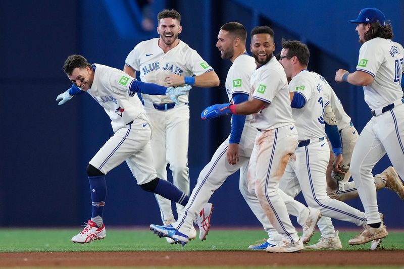 Jul 26, 2024; Toronto, Ontario, CAN; Toronto Blue Jays third baseman Ernie Clement (left) celebrates his walk off single to win the game against he Texas Rangers in the ninth inning at Rogers Centre. Mandatory Credit: John E. Sokolowski-USA TODAY Sports