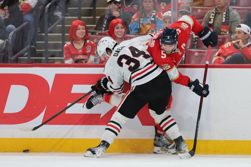 Oct 7, 2025; Sunrise, Florida, USA; Florida Panthers defenseman Aaron Ekblad (5) and Chicago Blackhawks center Colton Dach (34) battle for the puck during the second period at Amerant Bank Arena. Mandatory Credit: Sam Navarro-Imagn Images