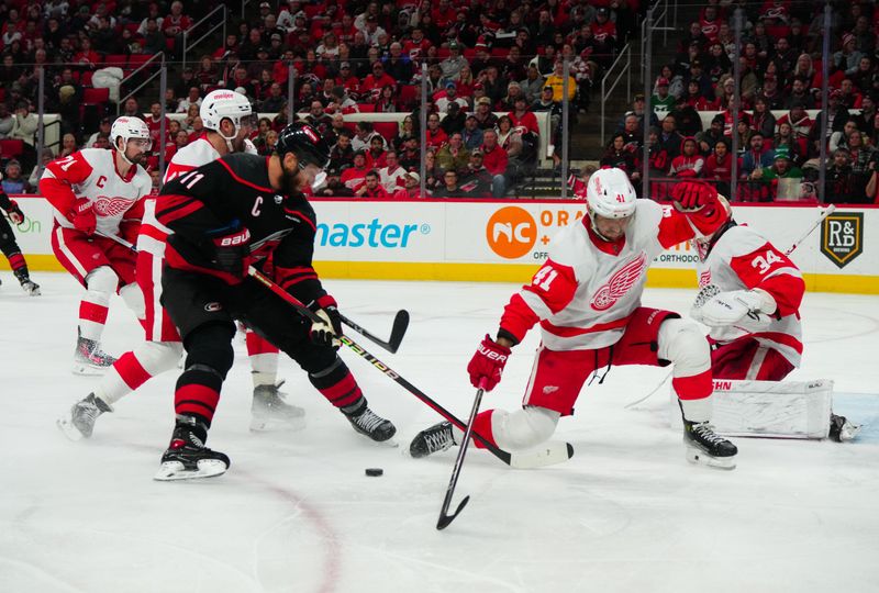 Jan 19, 2024; Raleigh, North Carolina, USA; Carolina Hurricanes center Jordan Staal (11) and Detroit Red Wings defenseman Shayne Gostisbehere (41) battle over the puck during the third period at PNC Arena. Mandatory Credit: James Guillory-USA TODAY Sports