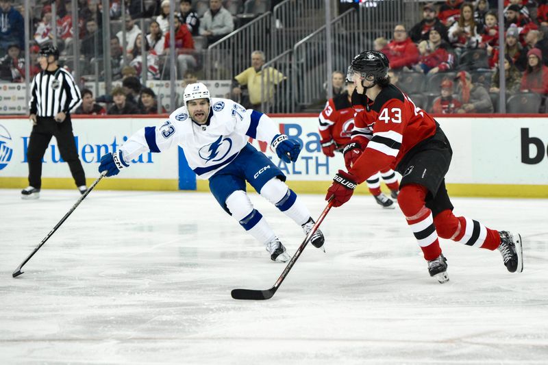 Feb 25, 2024; Newark, New Jersey, USA; New Jersey Devils defenseman Luke Hughes (43) skates with the puck while being defended by as Tampa Bay Lightning left wing Conor Sheary (73) defends during the first period at Prudential Center. Mandatory Credit: John Jones-USA TODAY Sports