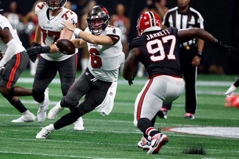 Tampa Bay Buccaneers quarterback Baker Mayfield (6) cuts in front of Atlanta Falcons defensive end Grady Jarrett (97) during the second half of an NFL football game Thursday, Oct. 3, 2024, in Atlanta. (AP Photo/Butch Dill)