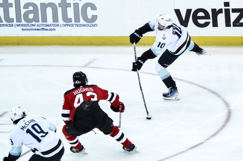 Feb 12, 2024; Newark, New Jersey, USA; Seattle Kraken center Matty Beniers (10) takes a shot as New Jersey Devils defenseman Luke Hughes (43) defends during the third period at Prudential Center. Mandatory Credit: John Jones-USA TODAY Sports