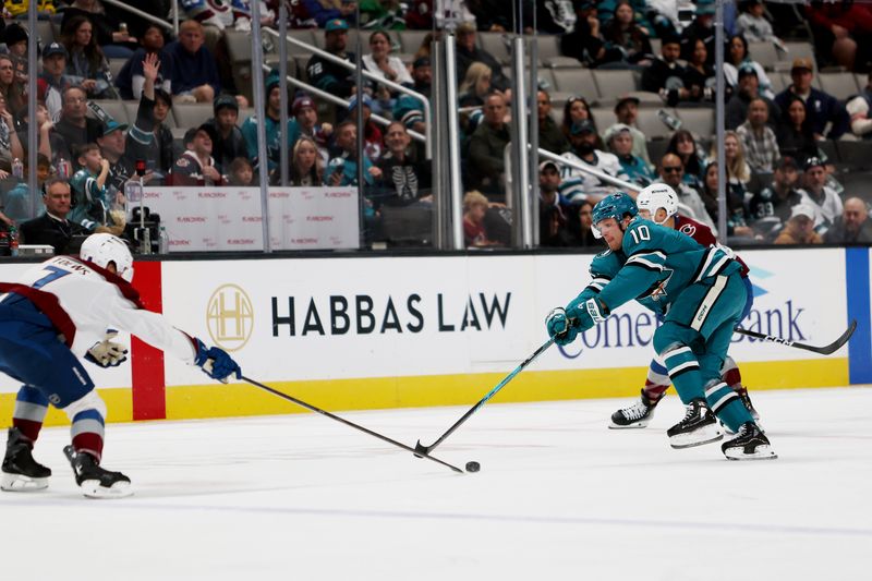 Nov 1, 2025; San Jose, California, USA; Colorado Avalanche defenseman Devon Toews (7) and San Jose Sharks center Ty Dellandrea (10) reach for the puck during the first period at SAP Center at San Jose. Mandatory Credit: Dennis Lee-Imagn Images