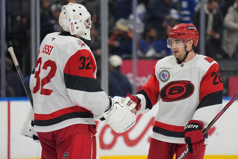 Nov 9, 2025; Toronto, Ontario, CAN; Carolina Hurricanes defenseman Sean Walker (26) congratulates goaltender Brandon Bussi (32) after a win against the Toronto Maple Leafs during the third period at Scotiabank Arena. Mandatory Credit: John E. Sokolowski-Imagn Images