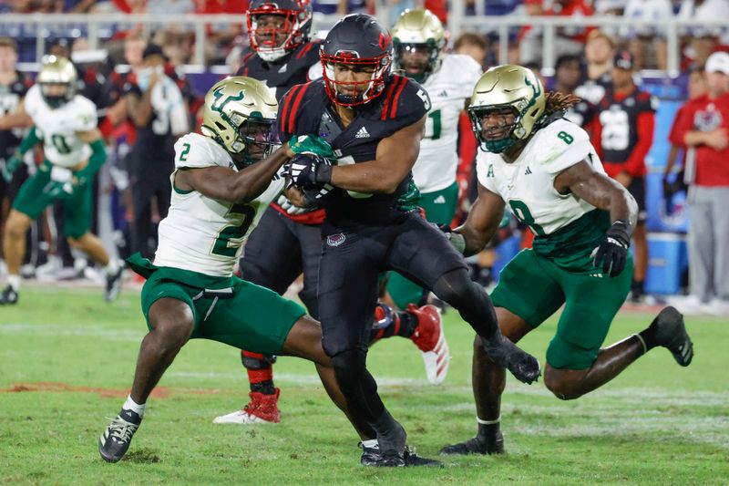 Nov 1, 2024; Boca Raton, Florida, USA;  Florida Atlantic Owls running back CJ Campbell Jr. (5) runs between South Florida Bulls defensive back Tavin Ward (2) and  linebacker DJ Gordon IV (8) during the second half at FAU Stadium. Mandatory Credit: Reinhold Matay-Imagn Images