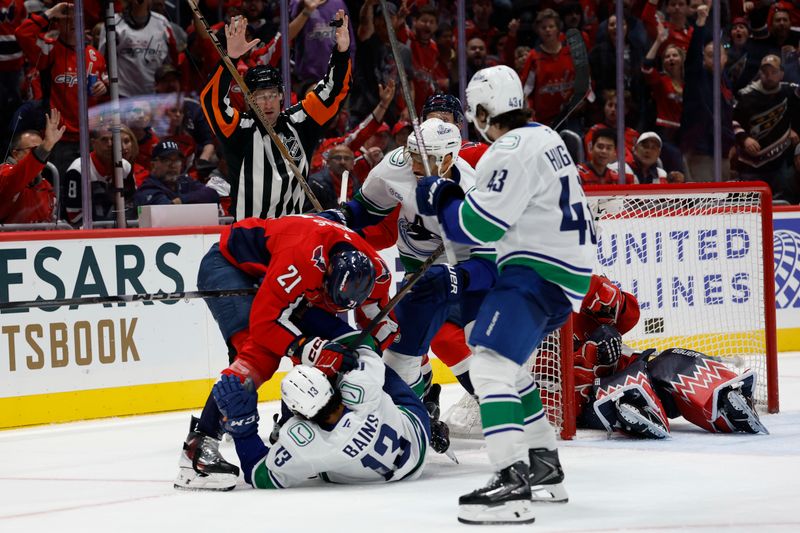 Oct 19, 2025; Washington, District of Columbia, USA; Vancouver Canucks left wing Arshdeep Bains (13) is hit by Washington Capitals center Aliaksei Protas (21) after crashing into Capitals goaltender Charlie Lindgren (79) during the second period at Capital One Arena. Mandatory Credit: Geoff Burke-Imagn Images