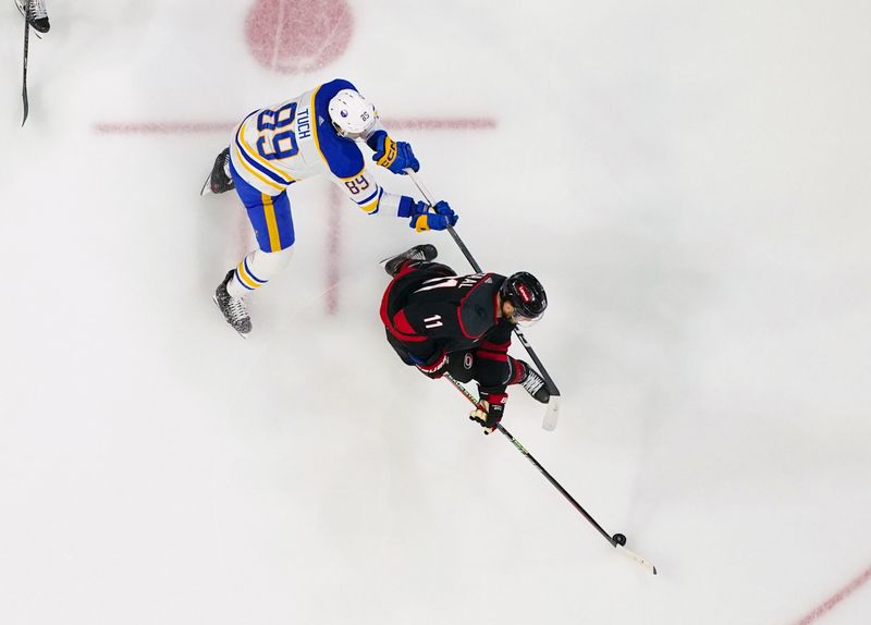 Dec 2, 2023; Raleigh, North Carolina, USA; Carolina Hurricanes center Jordan Staal (11) holds onto the puck against Buffalo Sabres right wing Alex Tuch (89) during the third period at PNC Arena. Mandatory Credit: James Guillory-USA TODAY Sports