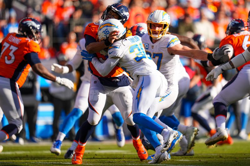 FILE - Denver Broncos quarterback Russell Wilson (3) is hit by Los Angeles Chargers cornerback Ja'Sir Taylor (36) during an NFL football game Jan. 8, 2023, in Denver. Taylor was penalized for roughing-the-passer on the play. The NFL’s competition committee will consider making roughing-the-passer penalties and personal-foul penalties subject to video review. (AP Photo/Jack Dempsey, File)