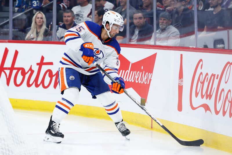 Sep 25, 2024; Winnipeg, Manitoba, CAN; Edmonton Oilers defenseman Beau Akey (82) looks to clear the puck against the Winnipeg Jets net during the second period at Canada Life Centre. Mandatory Credit: Terrence Lee-Imagn Images