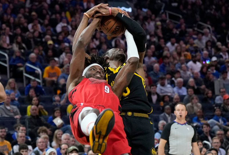 SAN FRANCISCO, CALIFORNIA - DECEMBER 23: Jonathan Kuminga #00 of the Golden State Warriors ties up the ball with Jerami Grant #9 of the Portland Trail Blazers for a jump ball during the first half at Chase Center on December 23, 2023 in San Francisco, California. NOTE TO USER: User expressly acknowledges and agrees that, by downloading and or using this photograph, User is consenting to the terms and conditions of the Getty Images License Agreement. (Photo by Thearon W. Henderson/Getty Images)