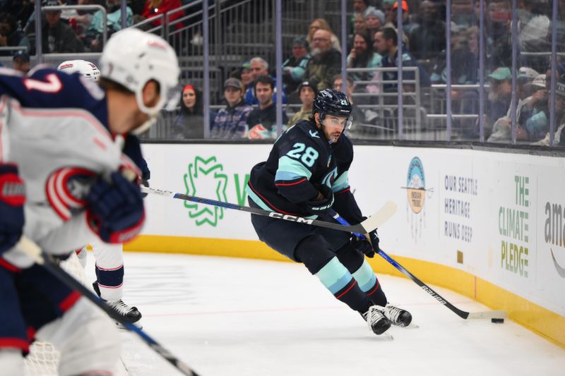 Nov 12, 2024; Seattle, Washington, USA; Seattle Kraken defenseman Joshua Mahura (28) plays the puck during the third period against the Columbus Blue Jackets at Climate Pledge Arena. Mandatory Credit: Steven Bisig-Imagn Images