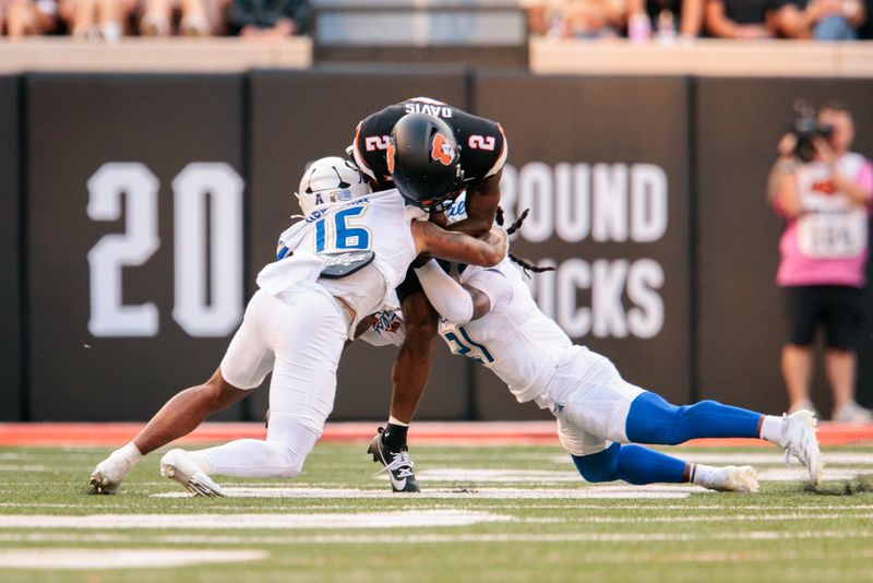 Sep 19, 2025; Stillwater, Oklahoma, USA; Oklahoma State Cowboys wide receiver Terrill Davis (2) is tackled by Tulsa Golden Hurricane linebacker Devin Robinson (16) and Tulsa Golden Hurricane safety Lento Smith Jr. (21) during the first half at Boone Pickens Stadium. Mandatory Credit: William Purnell-Imagn Images