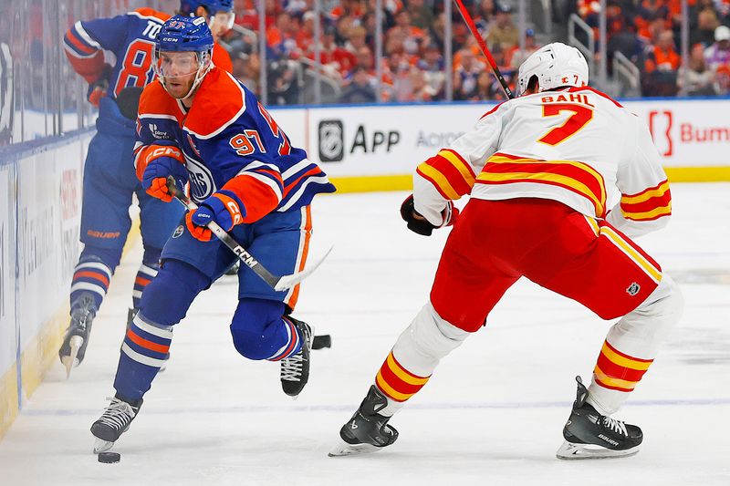 Oct 8, 2025; Edmonton, Alberta, CAN;  Edmonton Oilers forward Connor McDavid (97) chips the puck past Calgary Flames defensemen Kevin Bahl (7) during the third period at Rogers Place. Mandatory Credit: Perry Nelson-Imagn Images