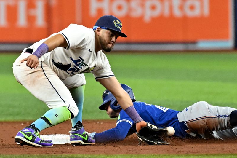 Sep 20, 2024; St. Petersburg, Florida, USA; Tampa Bay Rays second baseman Jonathan Aranda (62) attempts to catch the ball as Toronto Blue Jays shortstop Ernie Clement (28) slides in the eighth inning at Tropicana Field. Mandatory Credit: Jonathan Dyer-Imagn Images