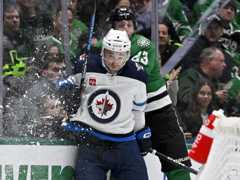 Feb 29, 2024; Dallas, Texas, USA; Winnipeg Jets defenseman Neal Pionk (4) checks Dallas Stars defenseman Esa Lindell (23) during the second period at the American Airlines Center. Mandatory Credit: Jerome Miron-USA TODAY Sports