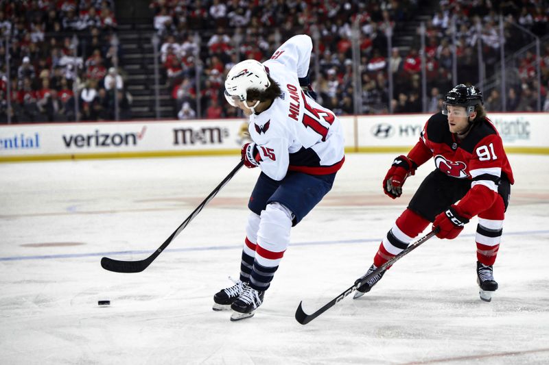 Nov 10, 2023; Newark, New Jersey, USA; Washington Capitals left wing Sonny Milano (15) passes the puck against as New Jersey Devils center Dawson Mercer (91) defends during the third period at Prudential Center. Mandatory Credit: John Jones-USA TODAY Sports