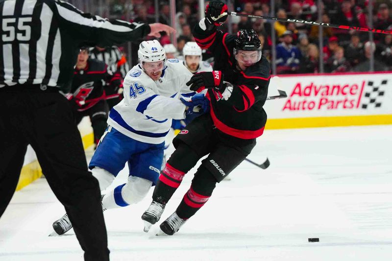 Nov 24, 2023; Raleigh, North Carolina, USA; Tampa Bay Lightning left wing Cole Koepke (45) and Carolina Hurricanes defenseman Dmitry Orlov (7) battle over the puck during the second period at PNC Arena. Mandatory Credit: James Guillory-USA TODAY Sports