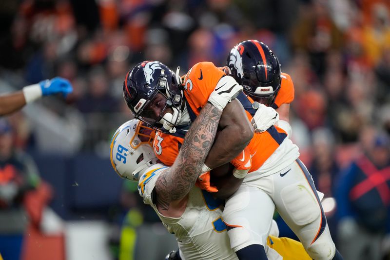 Los Angeles Chargers defensive tackle Scott Matlock (99) wraps up Denver Broncos running back Javonte Williams (33) in the second half of an NFL football game in Empower Field at Mile High Sunday, Dec. 31, 2023, in Denver. (AP Photo/David Zalubowski)